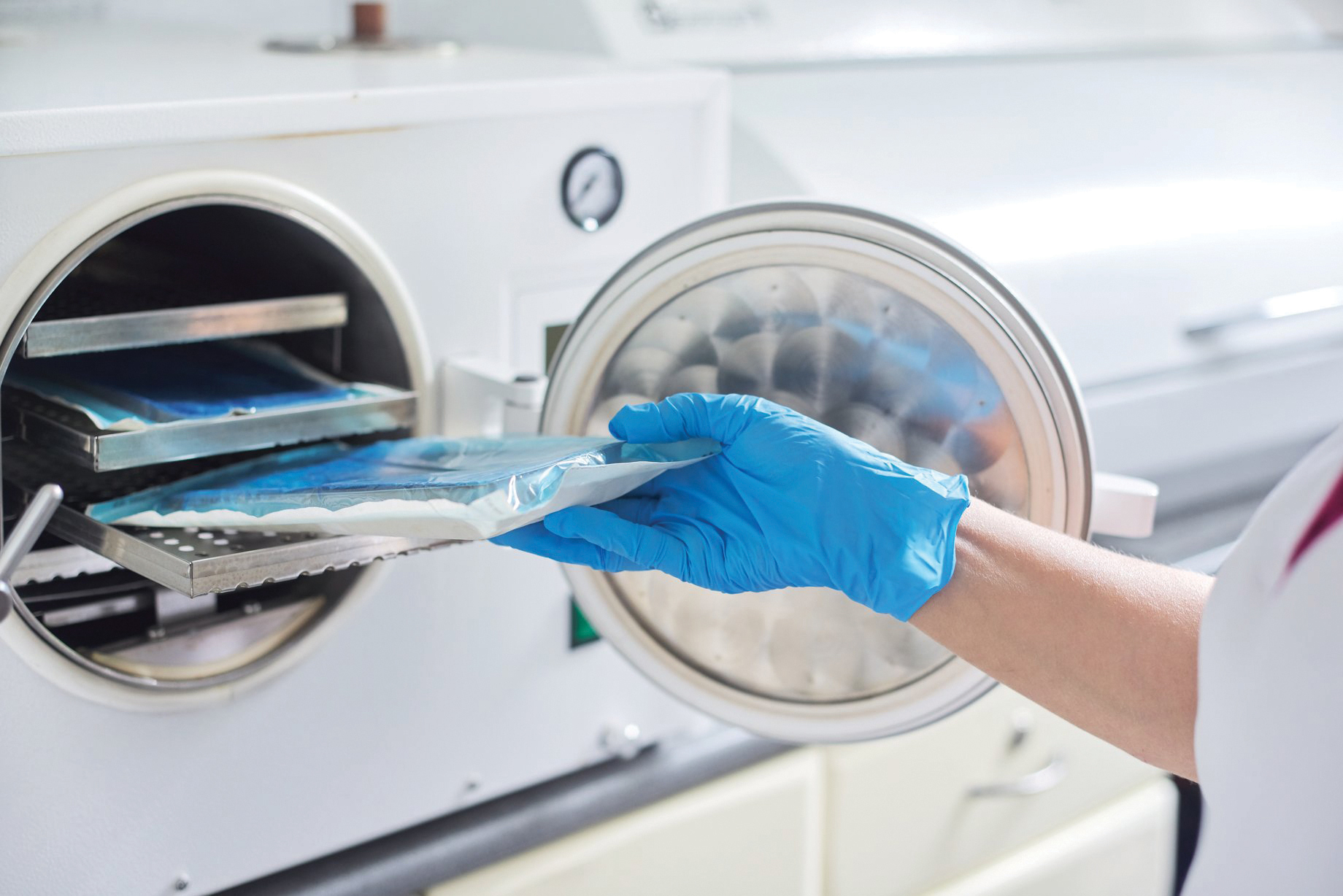 Female nurse doing sterilization of dental medical instruments in autoclave. Sterilization department at dental clinic